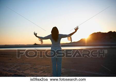 Rear view of woman with arms open on Cannon Beach at sunset, California, USA View Large Photo Image Stock Image - Rear view of woman with arms open on Cannon Beach at sunset, California, USA. Fotosearch