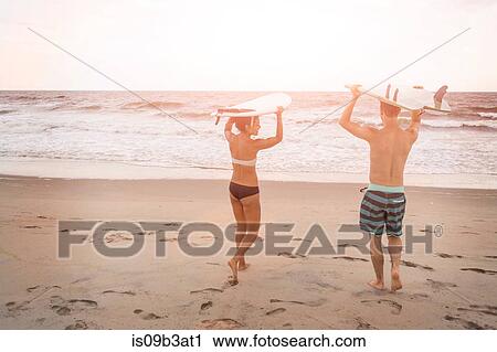 Rear view of young couple carrying surfboards on heads on Rockaway Beach, New York State, USA View Large Photo Image Stock Image - Rear view of young couple carrying surfboards on heads on Rockaway Beach, New York State, USA. Fotosearch