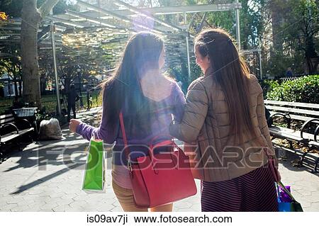 Rear view of young female adult twins strolling in park with shopping bags View Large Photo Image Stock Image - Rear view of young female adult twins strolling in park with shopping bags. Fotosearch