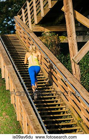 Rear view of young female running up wooden stairway View Large Photo Image Stock Photograph - Rear view of young female running up wooden stairway. Fotosearch