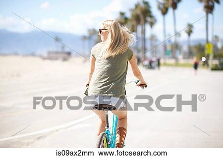 Rear view of young woman cycling at Venice Beach, Los Angeles, California, USA View Large Photo Image Picture - Rear view of young woman cycling at Venice Beach, Los Angeles, California, USA. Fotosearch
