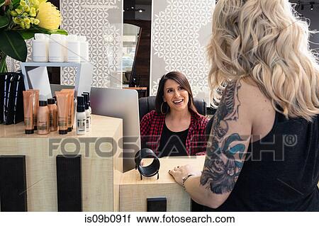 Stock Image - Receptionist attending to customer in hair salon. Fotosearch
