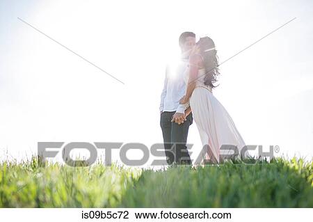 Romantic couple kissing on sunlit grassy hill View Large Photo Image Stock Image - Romantic couple kissing on sunlit grassy hill. Fotosearch