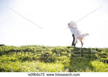 Romantic couple kissing on sunlit grassy hill View Large Photo Image Stock Image - Romantic couple kissing on sunlit grassy hill. Fotosearch