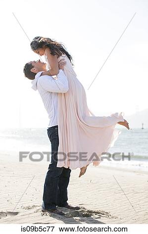 Romantic man holding up girlfriend on beach View Large Photo Image Stock Photo - Romantic man holding up girlfriend on beach. Fotosearch