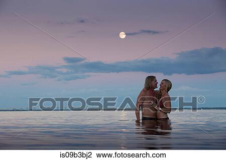 Stock Image - Romantic mature couple in sea at dusk, Santa Rosa Beach, Florida, USA. Fotosearch