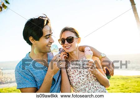 Stock Image - Romantic young couple at coast eating ice cream cones, Venice Beach, California, USA. Fotosearch