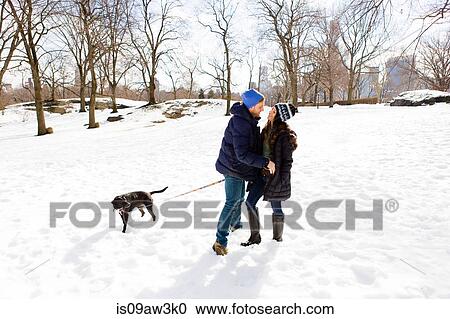 Romantic young couple standing together in snow with dog, Central Park, New York, USA View Large Photo Image Stock Image - Romantic young couple standing together in snow with dog, Central Park, New York, USA. Fotosearch