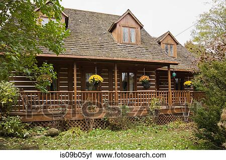 Stock Image - Rustic Canadian cottage style log home facade and landscaped front lawn in autumn, Quebec, Canada. Fotosearch