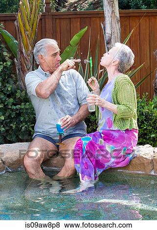 Senior couple blowing bubbles at pool View Large Photo Image Stock Photo - Senior couple blowing bubbles at pool. Fotosearch