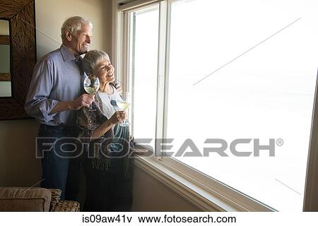 Senior couple looking out of window, holding glass of wine, smiling View Large Photo Image Stock Photo - Senior couple looking out of window, holding glass of wine, smiling. Fotosearch