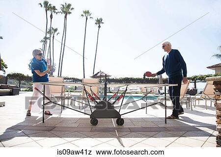 Stock Photo - Senior couple playing table tennis, outdoors. Fotosearch