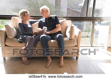 Senior couple, relaxing on sofa, sitting face to face, smiling View Large Photo Image Stock Image - Senior couple, relaxing on sofa, sitting face to face, smiling. Fotosearch
