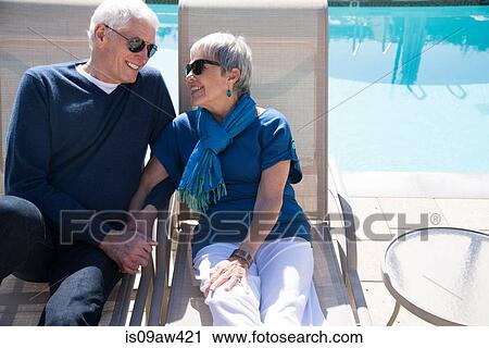 Senior couple relaxing on sun loungers beside pool View Large Photo Image Stock Image - Senior couple relaxing on sun loungers beside pool. Fotosearch