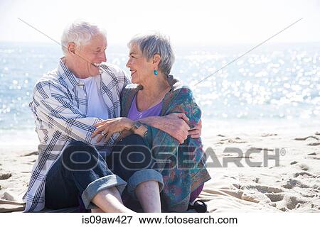 Senior couple sitting on beach, hugging, face to face, smiling View Large Photo Image Stock Photo - Senior couple sitting on beach, hugging, face to face, smiling. Fotosearch