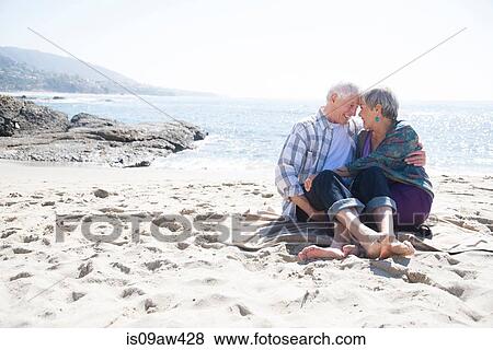 Senior couple sitting on beach, hugging, face to face, smiling View Large Photo Image Stock Photo - Senior couple sitting on beach, hugging, face to face, smiling. Fotosearch