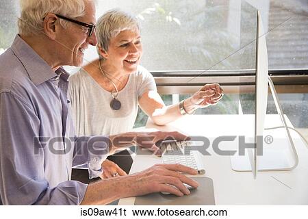 Senior couple using computer, looking at computer screen View Large Photo Image Stock Photograph - Senior couple using computer, looking at computer screen. Fotosearch
