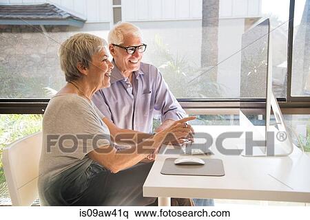 Senior couple using computer, looking at computer screen View Large Photo Image Stock Photography - Senior couple using computer, looking at computer screen. Fotosearch