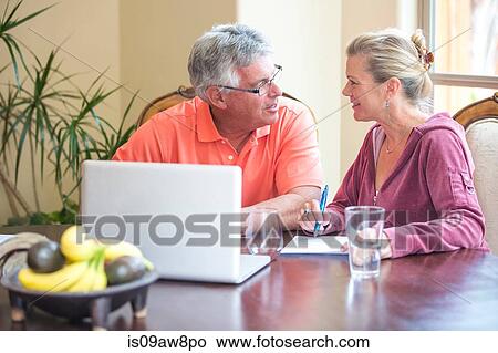 Senior couple using laptop and chatting at desk View Large Photo Image Picture - Senior couple using laptop and chatting at desk. Fotosearch