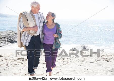 Senior couple walking along beach, smiling View Large Photo Image Stock Image - Senior couple walking along beach, smiling. Fotosearch
