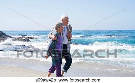 Senior couple walking along beach, smiling View Large Photo Image Stock Image - Senior couple walking along beach, smiling. Fotosearch