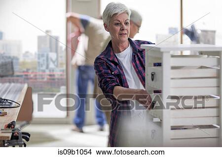 Picture - Senior female carpenter checking drawers in furniture making workshop. Fotosearch