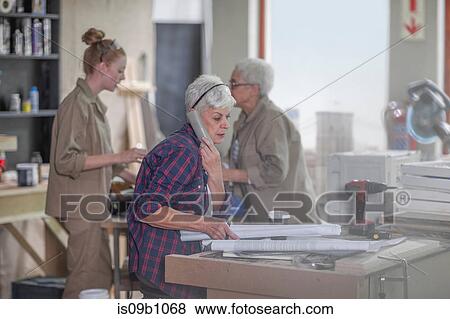 Senior female carpenter talking on cellphone in furniture making workshop View Large Photo Image Stock Photo - Senior female carpenter talking on cellphone in furniture making workshop. Fotosearch