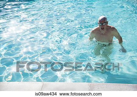 Picture - Senior man emerging from water in outdoor swimming pool. Fotosearch
