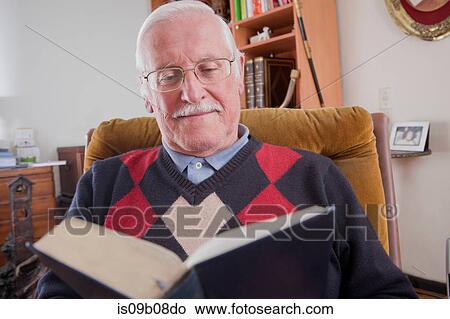 Picture - Senior man reading book at home. Fotosearch