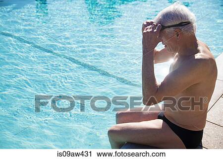Stock Image - Senior man sitting on edge of outdoor swimming pool. Fotosearch