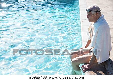 Senior man sitting on edge of outdoor swimming pool, towel around shoulders View Large Photo Image Stock Photo - Senior man sitting on edge of outdoor swimming pool, towel around shoulders. Fotosearch