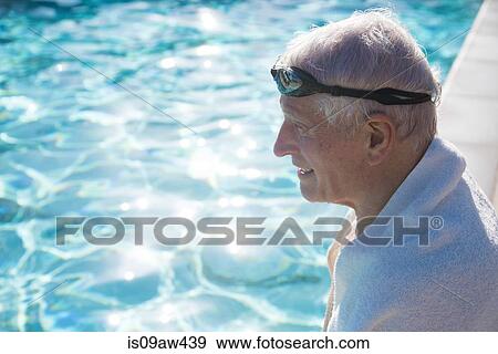Senior man sitting on edge of outdoor swimming pool, towel around shoulders View Large Photo Image Stock Photo - Senior man sitting on edge of outdoor swimming pool, towel around shoulders. Fotosearch