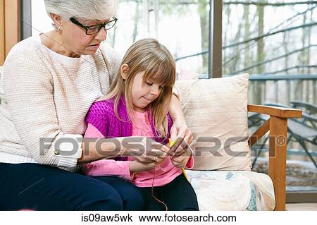 Senior woman and granddaughter knitting on living room sofa View Large Photo Image Stock Image - Senior woman and granddaughter knitting on living room sofa. Fotosearch