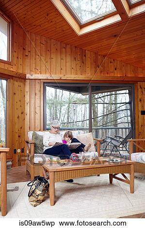Senior woman and granddaughter reading story book on living room sofa View Large Photo Image Stock Photography - Senior woman and granddaughter reading story book on living room sofa. Fotosearch
