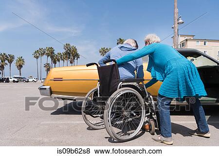 Senior woman helping husband in wheelchair by vintage car at Venice Beach, California, USA View Large Photo Image Stock Photo - Senior woman helping husband in wheelchair by vintage car at Venice Beach, California, USA. Fotosearch