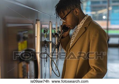 Serious young businessman talking on train station pay phone View Large Photo Image Stock Image - Serious young businessman talking on train station pay phone. Fotosearch