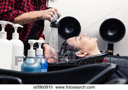Stock Image - Shampoo girl rinsing customer's hair in salon. Fotosearch
