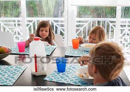 Siblings at dining table eating breakfast View Large Photo Image Stock Photograph - Siblings at dining table eating breakfast. Fotosearch