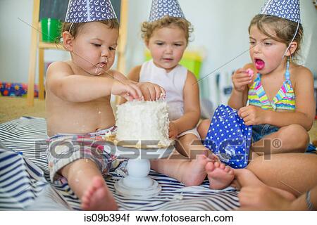 Siblings looking at boy poking fingers into birthday cake View Large Photo Image Stock Image - Siblings looking at boy poking fingers into birthday cake. Fotosearch