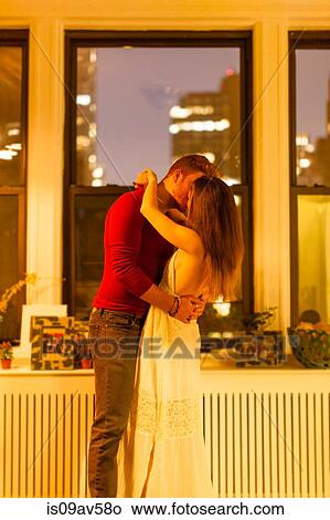 Side view of couple in apartment standing kissing View Large Photo Image Picture - Side view of couple in apartment standing kissing. Fotosearch