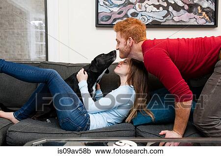 Side view of couple on sofa kissing pet dog smiling View Large Photo Image Stock Image - Side view of couple on sofa kissing pet dog smiling. Fotosearch