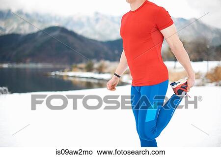 Side view of male runner stretching leg by snow covered lakeside, Lake Kawaguchiko, Mount Fuji, Japan View Large Photo Image Picture - Side view of male runner stretching leg by snow covered lakeside, Lake Kawaguchiko, Mount Fuji, Japan. Fotosearch