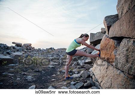 Stock Photography - Side view of woman leg raised stretching against rock. Fotosearch