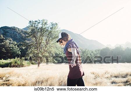 Side view of woman walking in field by mountains, Malibu, California, USA View Large Photo Image Stock Photography - Side view of woman walking in field by mountains, Malibu, California, USA. Fotosearch