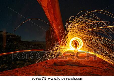 Silhouetted person creating yellow circular light trails on arch rock formation at night, Utah, USA View Large Photo Image Stock Photograph - Silhouetted person creating yellow circular light trails on arch rock formation at night, Utah, USA. Fotosearch