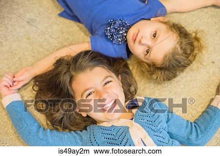Picture - Sisters lying down on floor. Fotosearch