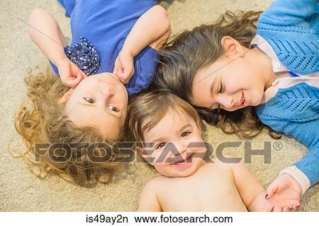 Sisters lying down on floor View Large Photo Image Picture - Sisters lying down on floor. Fotosearch