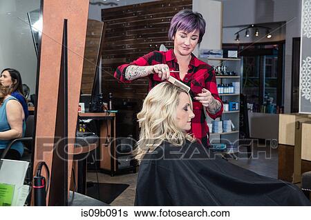 Stock Photograph - Stylist attending to customer in hair salon. Fotosearch