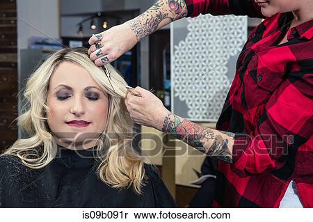 Stock Photography - Stylist attending to customer in hair salon. Fotosearch