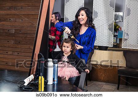 Stylist curling girl's hair in salon View Large Photo Image Picture - Stylist curling girl's hair in salon. Fotosearch